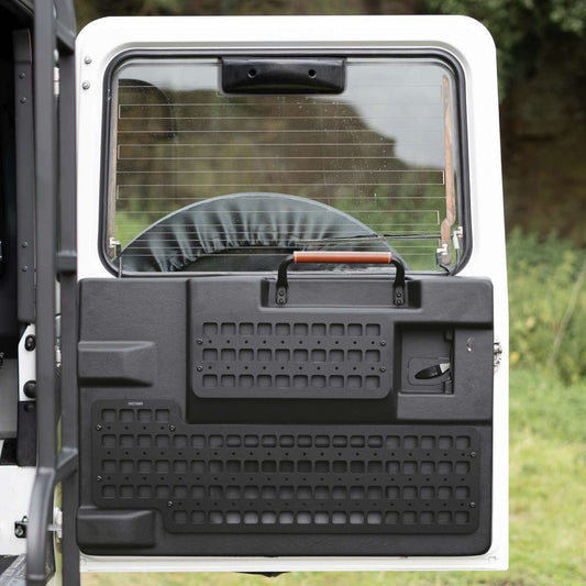 Back door of a vehicle with a storage panel on a grassy background